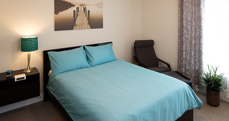 A bed with blue sheets and pillows in a room.