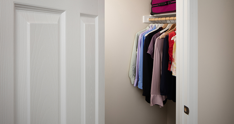 A closet with clothes hanging on the rail.