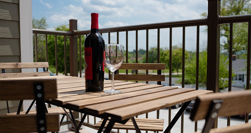 A bottle of wine and glass on an outdoor table.