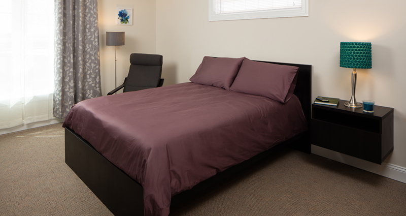 A bed with purple sheets and pillows on it.