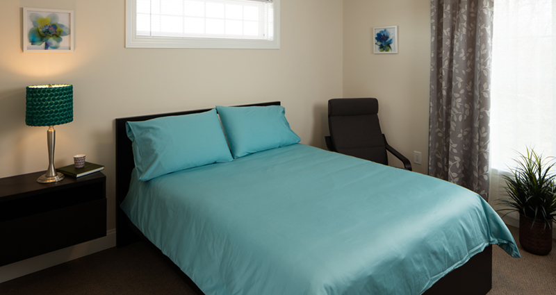 A bed with blue sheets and pillows in a room.